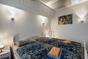 Un dormitorio con cama, mesita de noche, lámpara e iluminación en la pared.