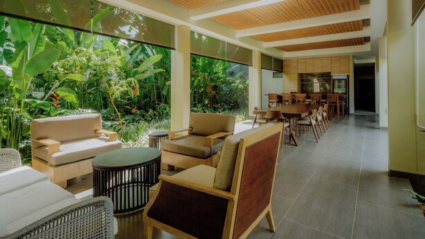 A spacious indoor area with a long dining table, multiple chairs, and a seating area with sofas and a coffee table. - Sunyi Ubud (Payangan)