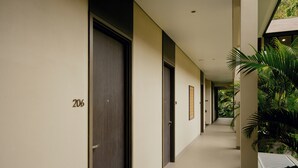 A corridor with doors numbered 206, lined with plants and a bench. - Sunyi Ubud (Payangan)