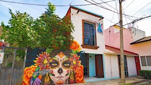 A building with a mural of a Day of the Dead face and colorful flowers. - Residencia en la ciudad de Oaxaca (Oaxaca de Juárez)