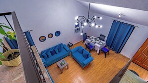 A modern living room with a blue sofa, a dining table, and a chandelier. - Residencia en la ciudad de Oaxaca (Oaxaca de Juárez)