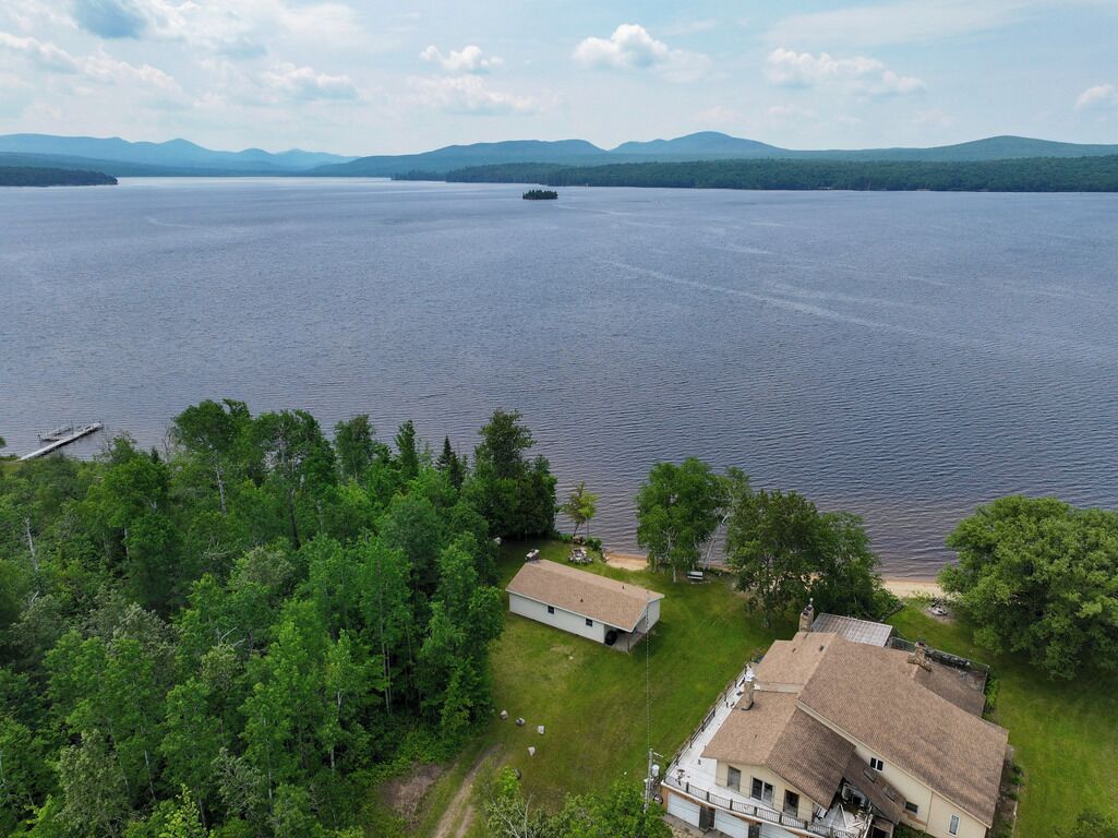 An aerial view of a lakeside property with a house, a dock, and a boat.