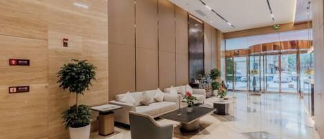 Eine moderne Lobby mit einer Rezeption, einer Sitzecke und großen Fenstern.