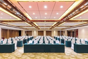 A conference room with rows of tables and chairs, a high ceiling with recessed lighting, and a carpeted floor. - Antai Century Hotel (Chengdu)