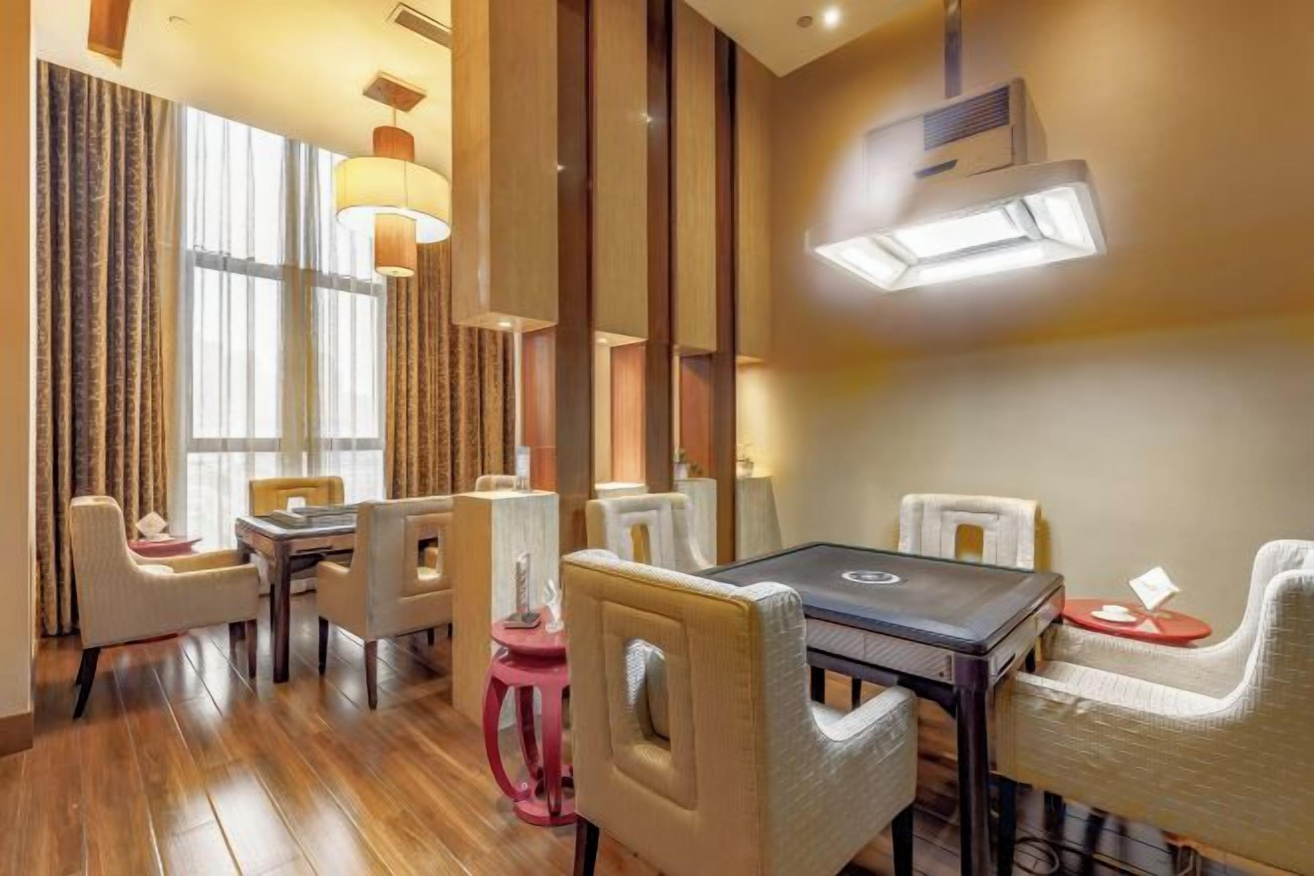 A hotel dining area with a long table, multiple chairs, and a modern chandelier.