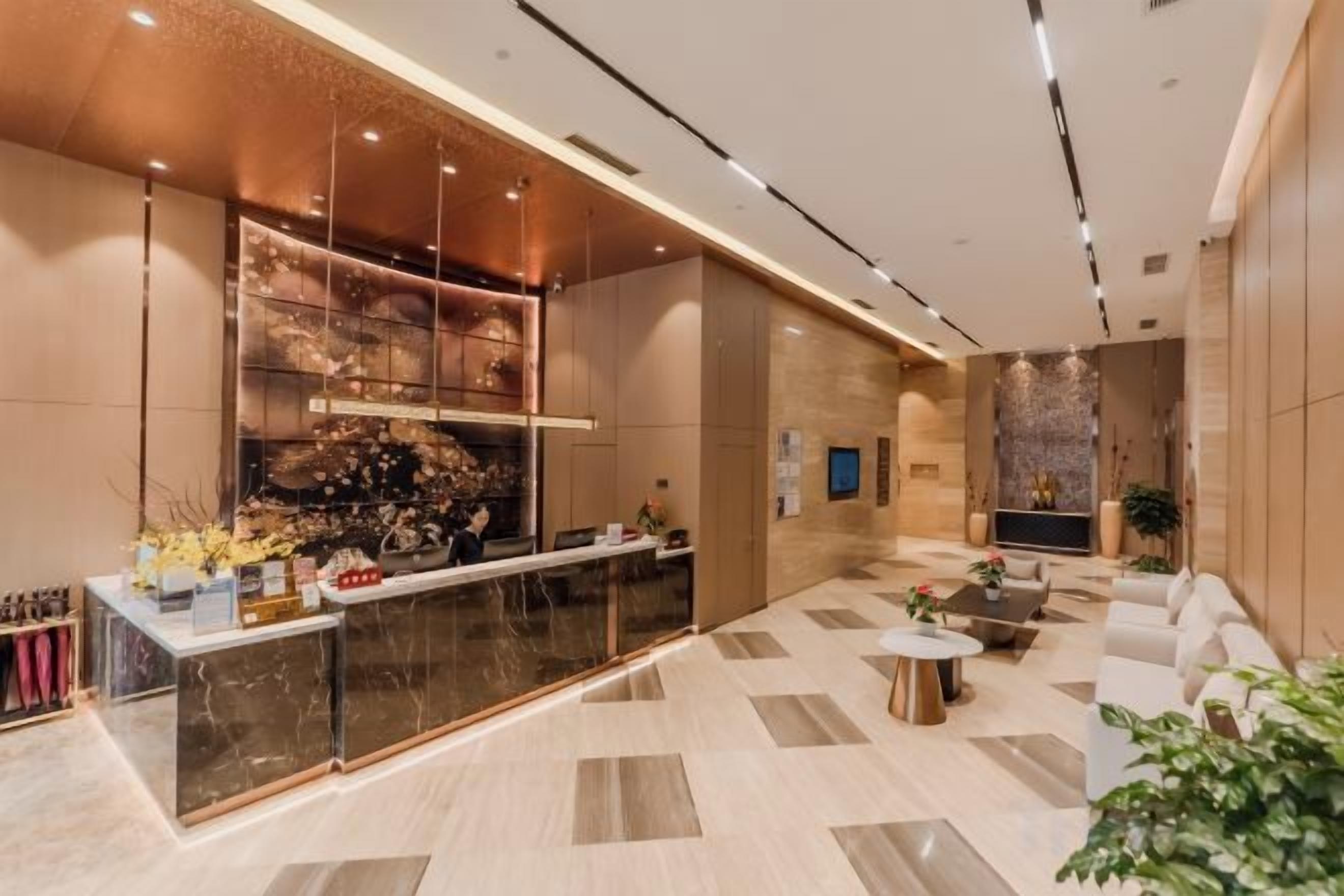 A modern lobby with a reception desk, seating area, and a decorative wall.