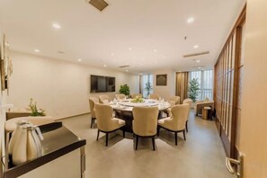 A modern dining area with a round table, multiple chairs, and a TV mounted on the wall. - Antai Century Hotel (Chengdu)