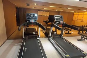 A gym with two treadmills, a wall-mounted exercise bike, and a mirror. - Antai Century Hotel (Chengdu)