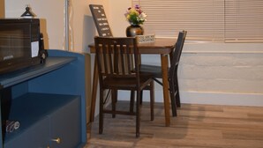 A dining area with a table, chairs, a vase with flowers, a sign reading "YOU ARE MY SUNSHINE," a lamp, and a blue cabinet.