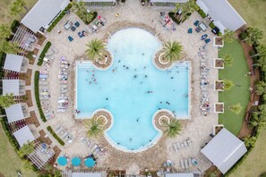 An aerial view of a resort with a central swimming pool surrounded by lounge areas and palm trees. - Shine on the Shore by AvantStay | Pool + Golf Cart (Inlet Beach)