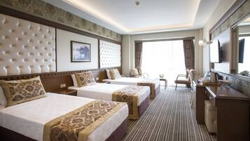 Een hotelkamer met twee bedden, een bureau, een stoel, een televisie en een groot raam.