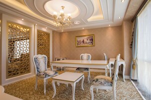 Un comedor con una mesa y sillas blancas, una araña y un cuadro en la pared.