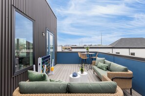 En takterrass med modern design, med en sittgrupp bestående av en soffa och stolar, ett litet bord och ett stort fönster.