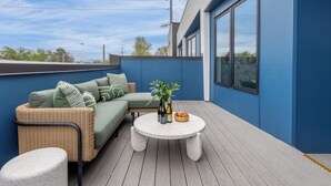 En balkon med en fletningssofa, et rundt bord og en lille skammel.