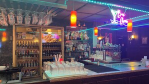 A bar area with shelves of liquor bottles, a glass display case, and a neon sign. - Outlook Motor Hotel (Outlook)