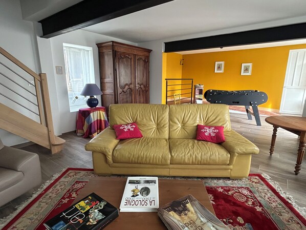 A living room with a sofa, a coffee table, a lamp, a cabinet, and a futsal table.