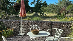 A patio with a round table and white chairs, a stone wall, and an umbrella. - UNE Maison DE Famille A LA Campagne (Gièvres)