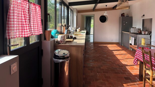A kitchen with a large window, a dining area with a table and chairs, and a view of the outdoors. - UNE Maison DE Famille A LA Campagne (Gièvres)