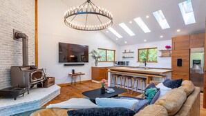 Ein modernes Wohnzimmer mit Kamin, einer großen Couch, einem Essbereich und einer Küche inklusive Kühlschrank und Mikrowelle.