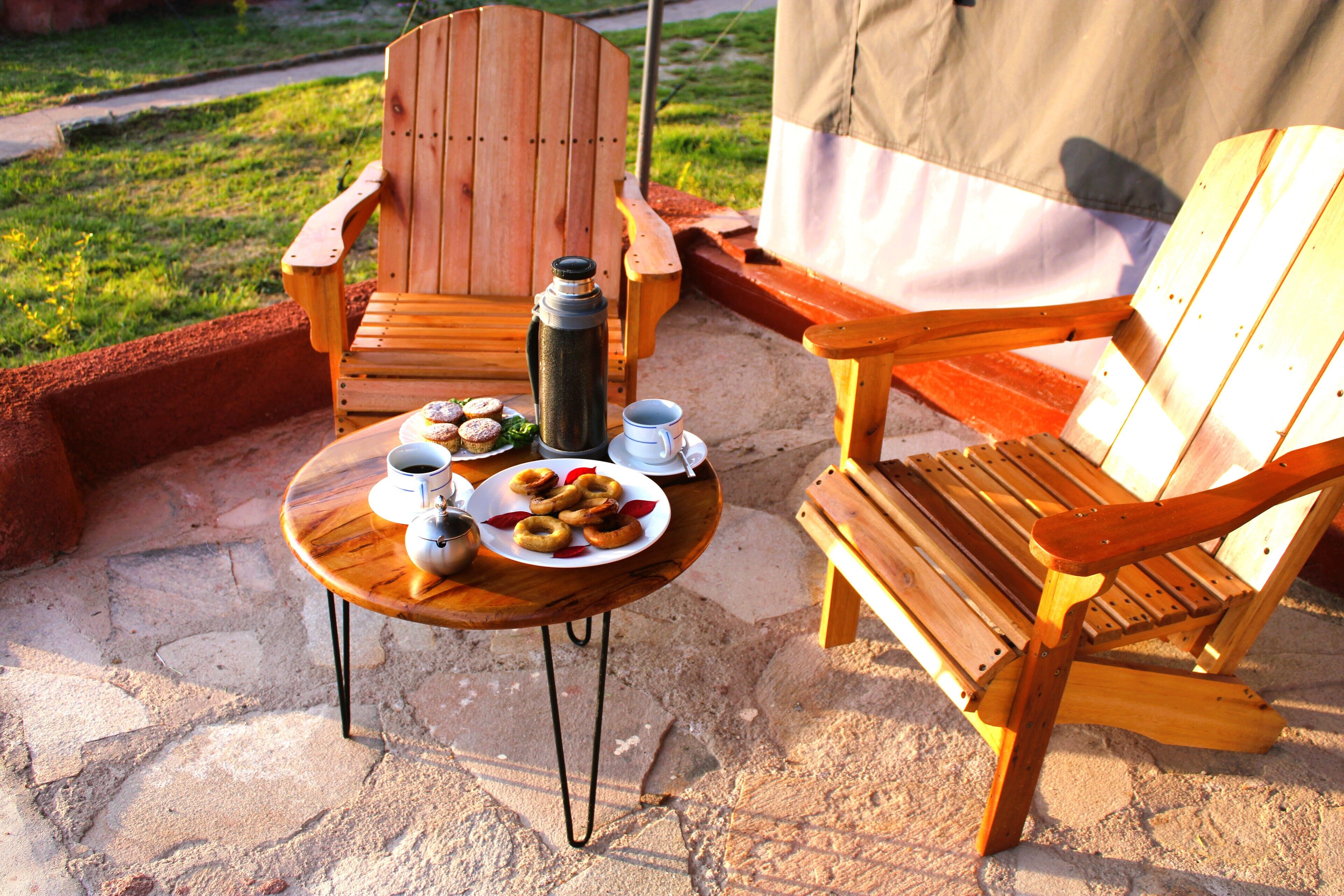 Een terras met houten stoelen en een tafel, gedekt met eten en drinken.
