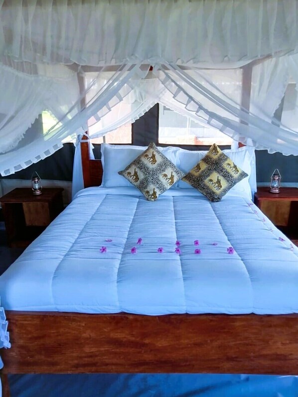 Una cama con ropa blanca, dos almohadas decorativas y un dosel.