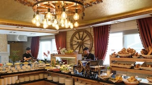 A buffet setup with a variety of food items, a large decorative wheel, and a chandelier.