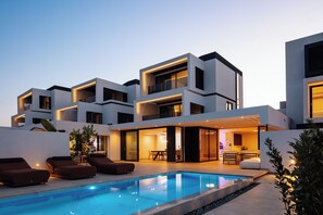 A modern house with a swimming pool, outdoor seating, and a well-lit interior. - Nuera III: Modern 3BR Villa, 300m from the Beach (Chania)