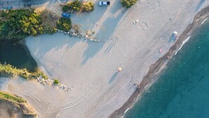 An aerial view of a beach with clear waters, a few people, and some trees.