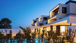 A modern multi-story building with a pool in the foreground.