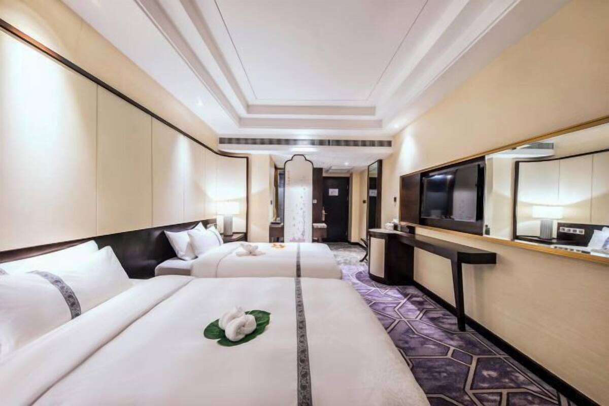 Une chambre d’hôtel avec deux lits, une télévision, un bureau et un miroir.