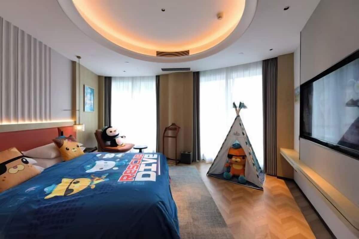 Une chambre d’hôtel avec un lit, une télévision, une tente et une fenêtre avec des rideaux.