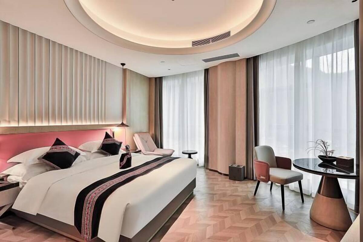 Une chambre d’hôtel avec un grand lit, une table ronde et une chaise.