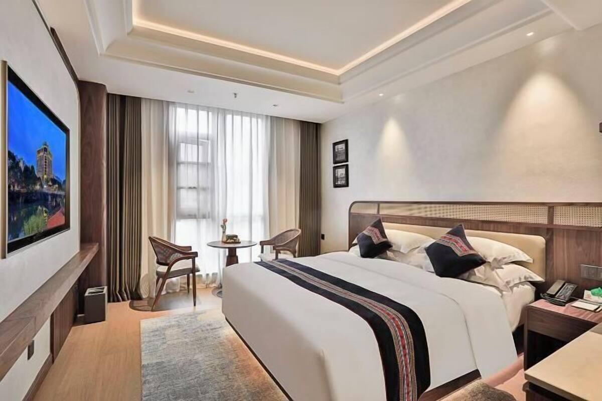 Une chambre d’hôtel avec un grand lit, une télévision, une petite table et une chaise.