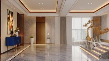 A spacious lobby with a marble floor, a blue console table, a large abstract painting, a reception desk, and a staircase with a tree sculpture.