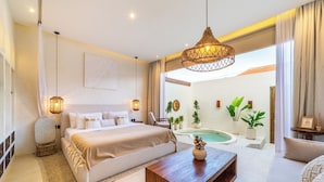 A modern bedroom with a large bed, a wooden coffee table, a hanging light fixture, and a view of a swimming pool. - OriVista Luxe 1BR Designer Pool Villa in Canggu (Canggu)