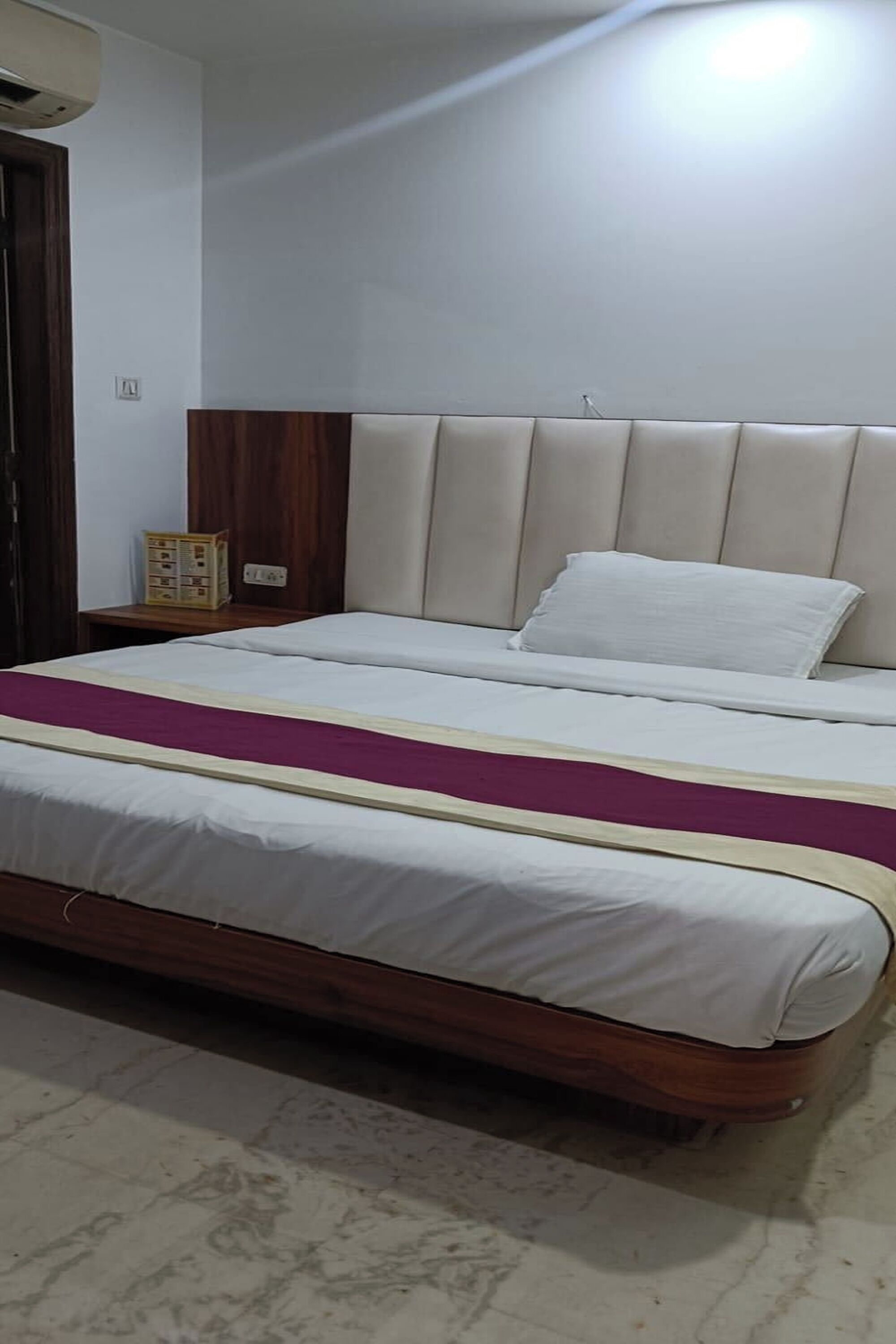 A bedroom with a bed, wooden headboard, bedside table, and a nightstand.