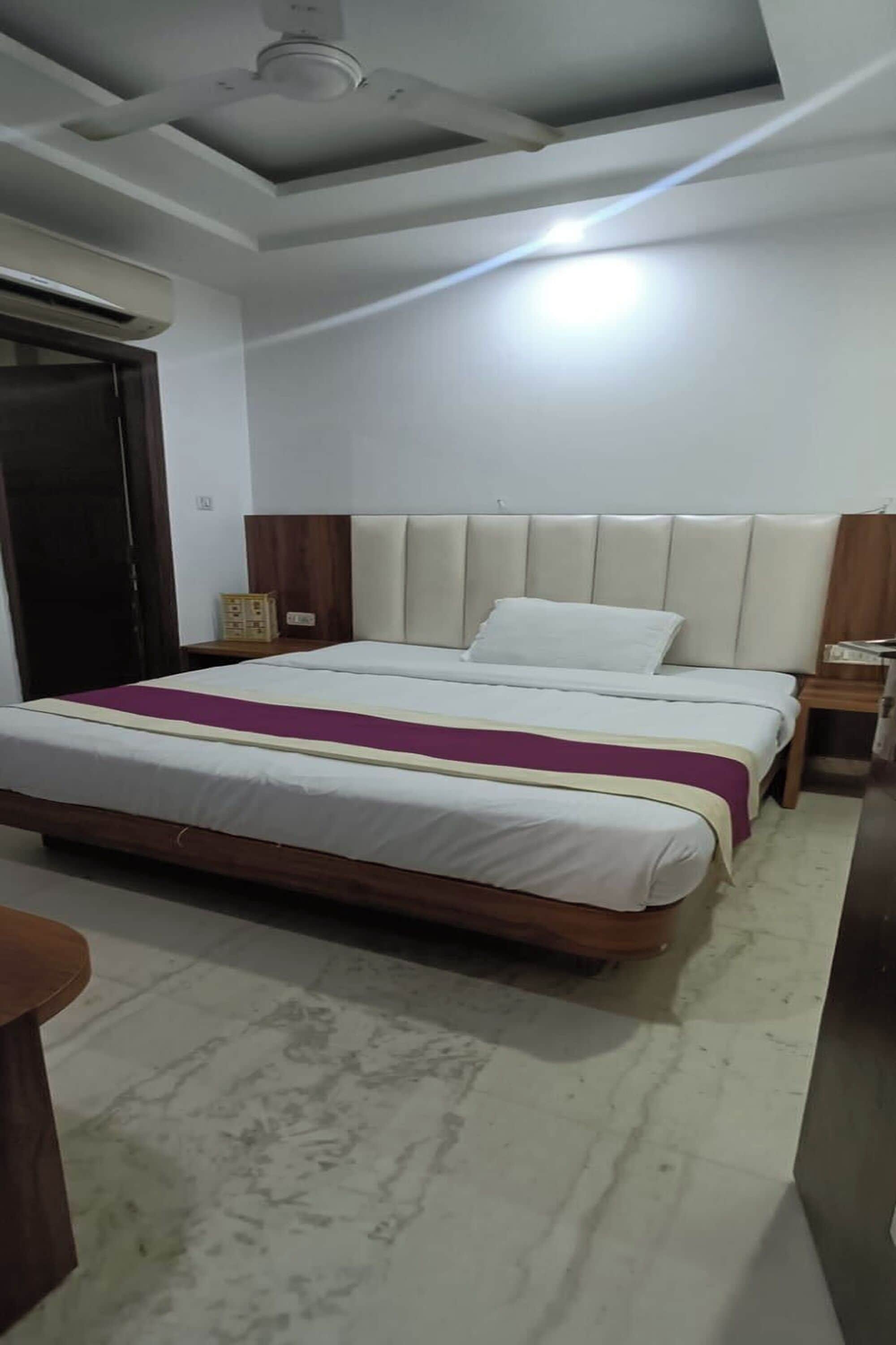 A bedroom with a bed, wooden headboard, bedside tables, and a ceiling fan.