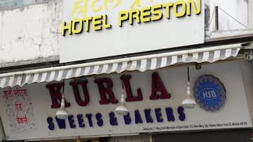 A sign for Hotel Preston and a shop named Kurla Sweets & Bakers.