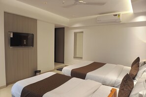 A hotel room with two beds, a TV, an air conditioning unit, and a mirror. - Hotel Preston (Mumbai)