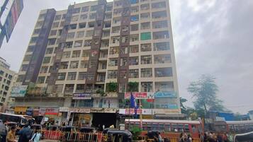 A multi-story building with balconies and various shops on the ground floor.