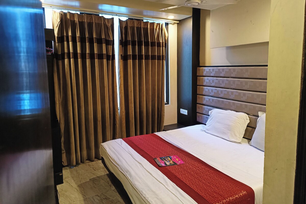 A hotel room with a bed, curtains, a headboard, and a nightstand.