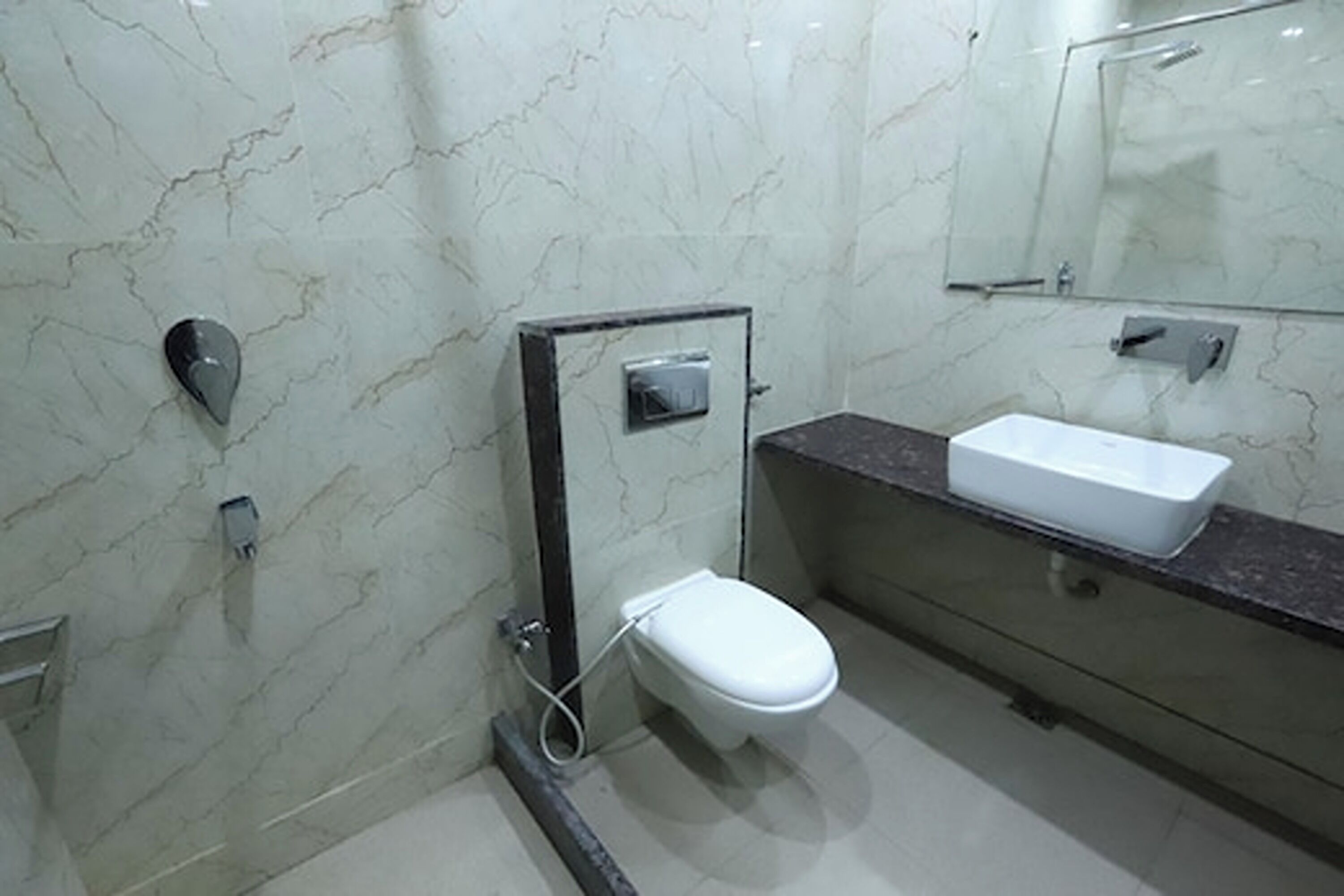 Une salle de bain moderne avec des toilettes blanches, un lavabo rectangulaire et un miroir au-dessus du lavabo.