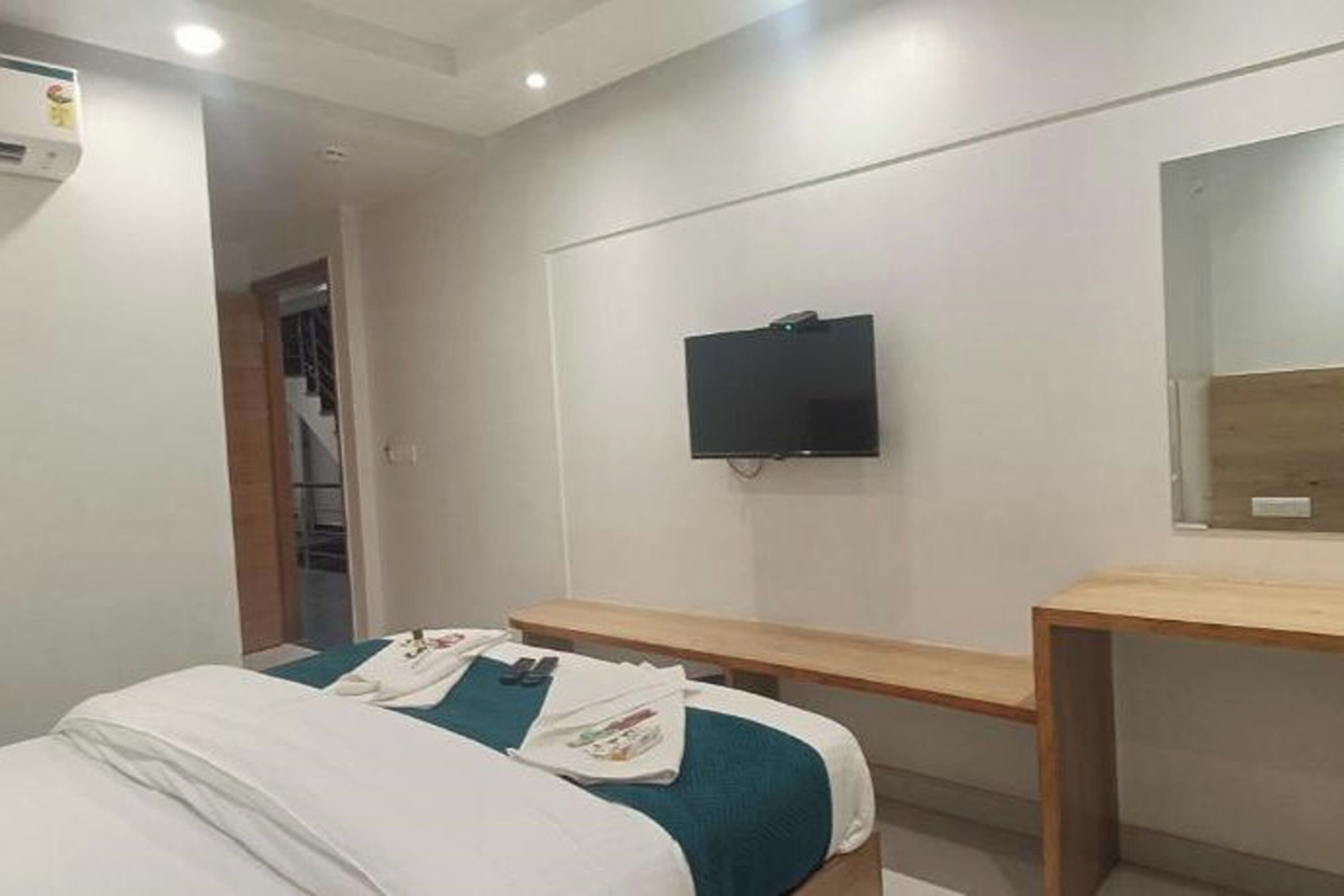 Une chambre d’hôtel équipée d’un lit, d’un bureau, d’un téléviseur fixé au mur et d’un miroir.