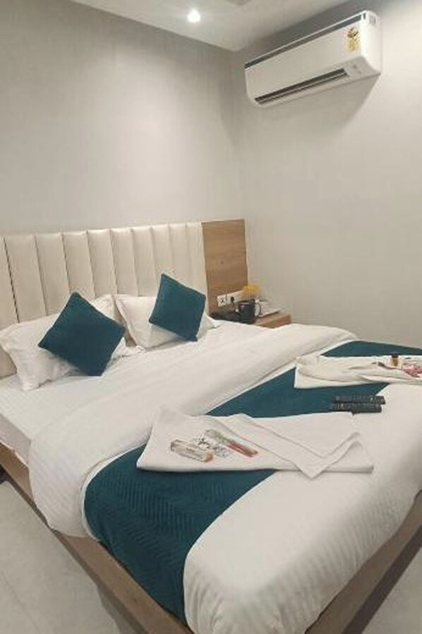 A hotel room with a bed, pillows, a nightstand, and an air conditioning unit. - Hotel Shree Sai Dham Near New Delhi Railway Station, Paharganj (New Delhi)