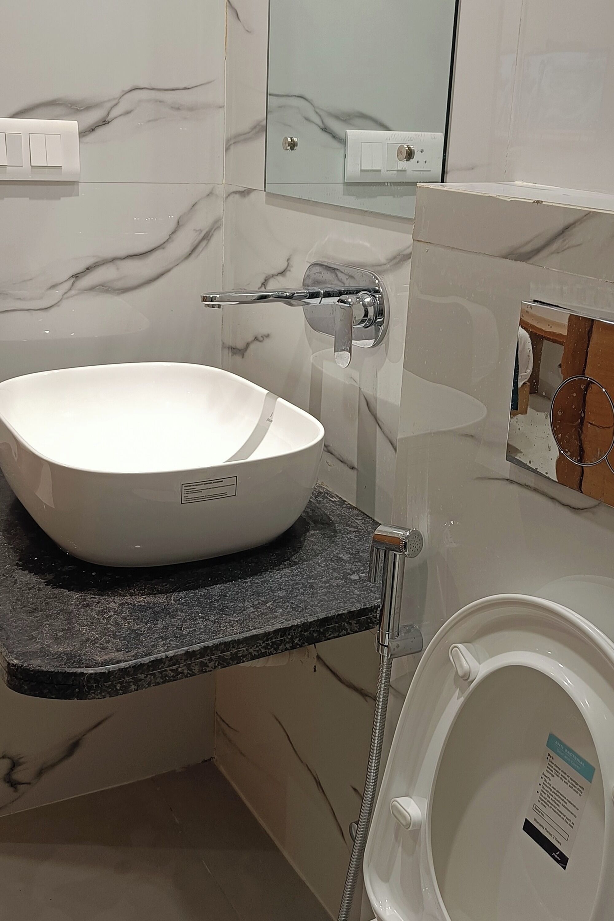 A bathroom with a white vessel sink, a built-in toilet, and a shower.