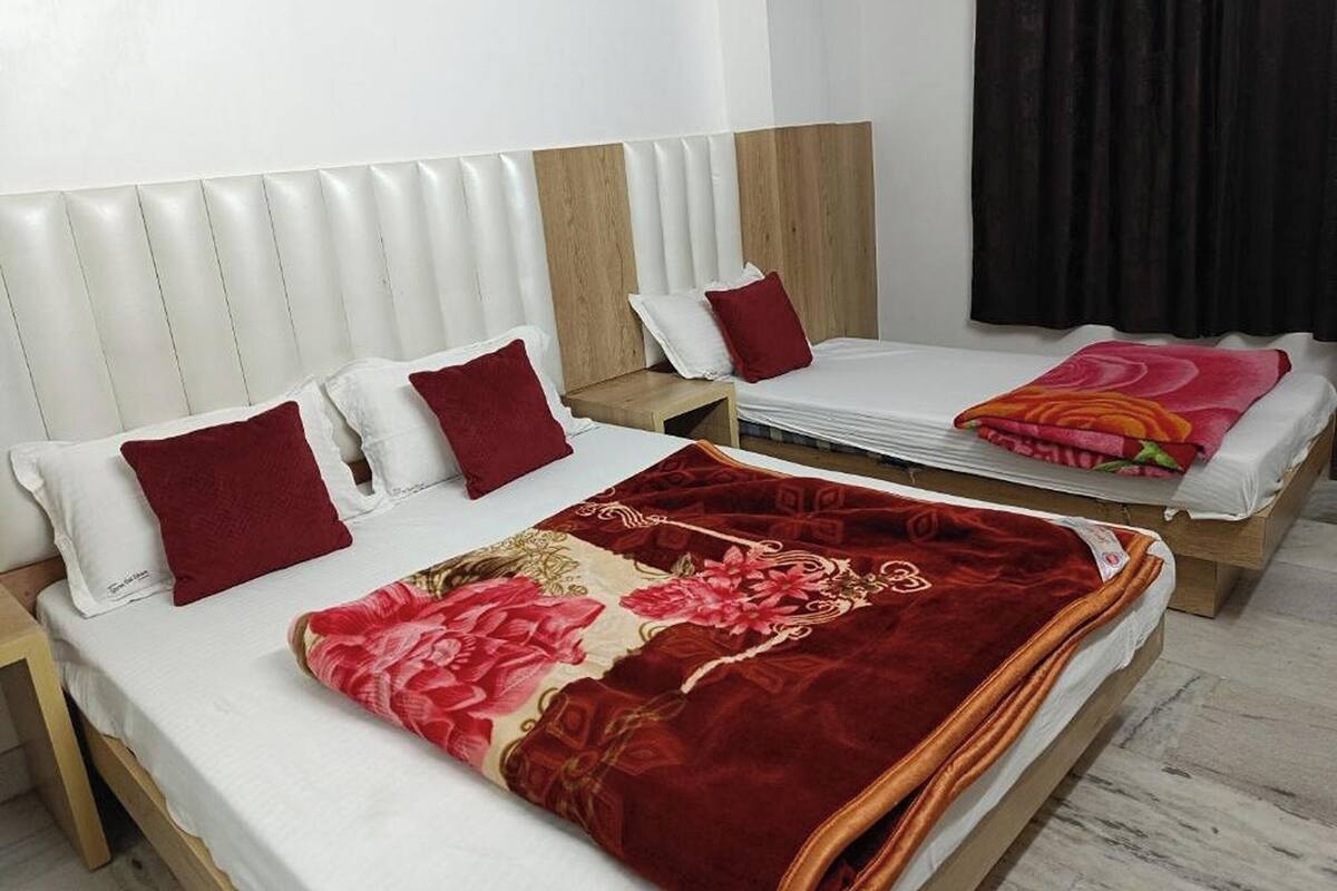 Une chambre d’hôtel avec deux lits, chacun doté de draps blancs et d’oreillers rouges. Les lits ont des cadres en bois et des têtes de lit avec un motif matelassé.