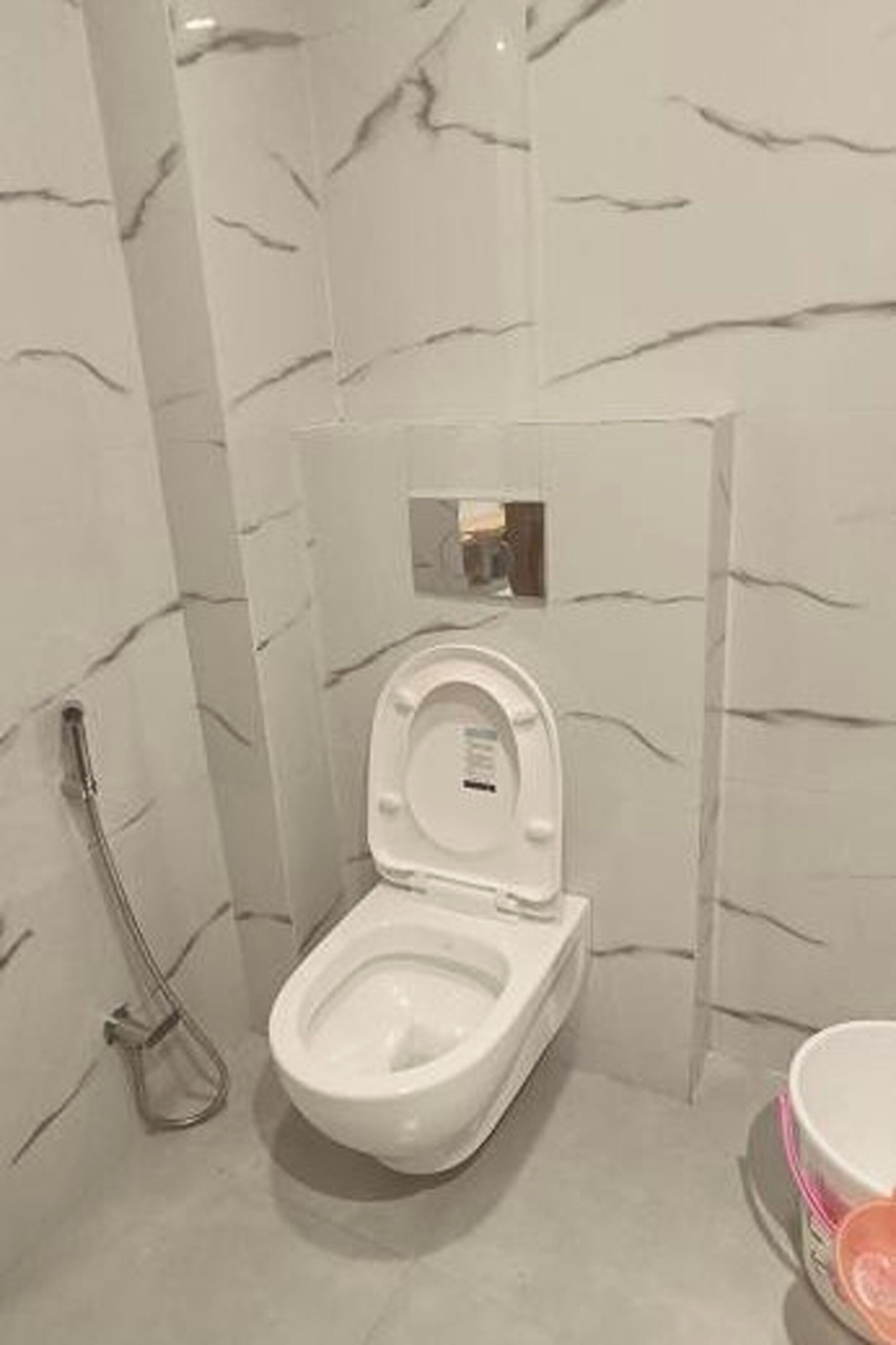A bathroom with a toilet, bidet, and a small mirror.