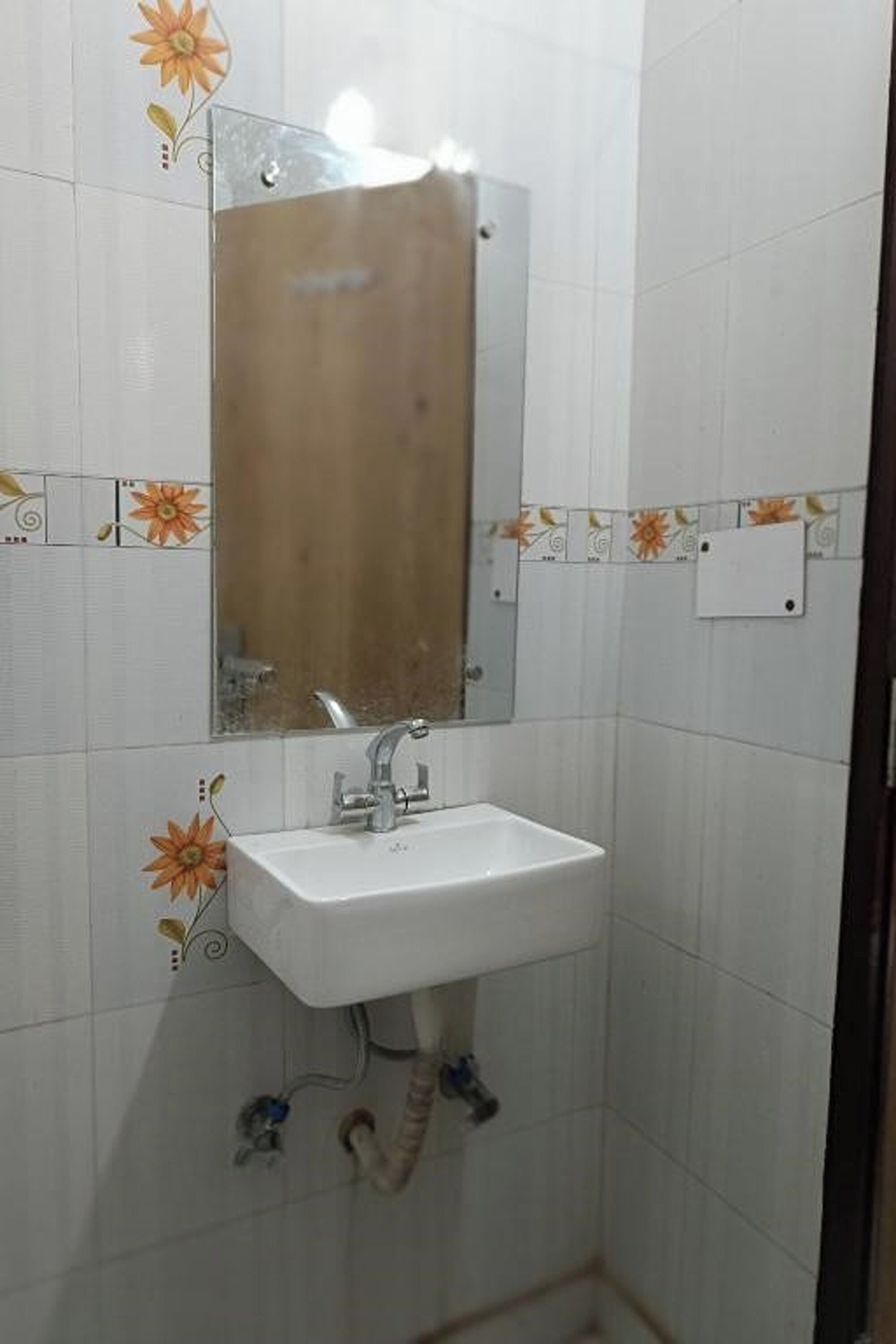 A bathroom with a white sink, a mirror, and floral-patterned tiles.