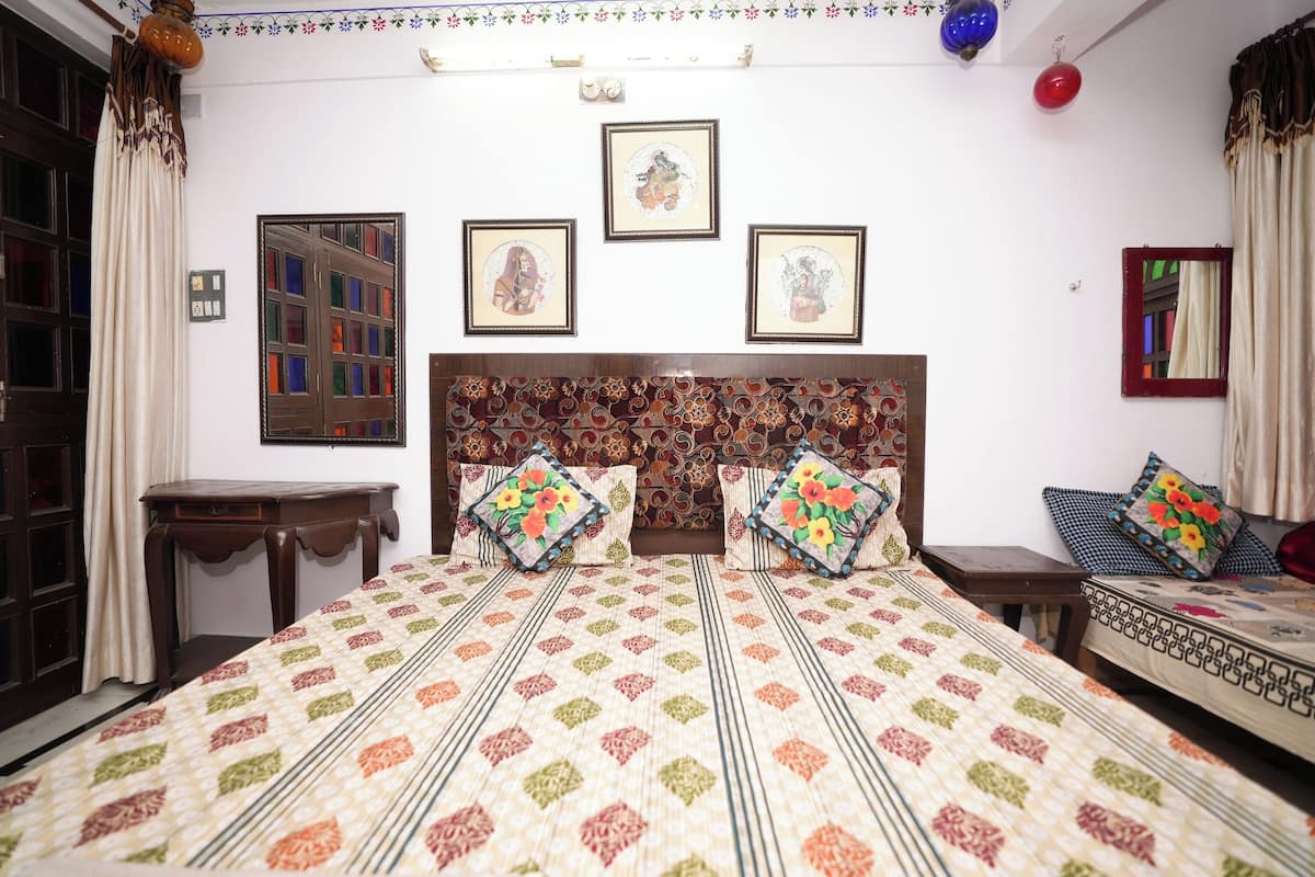 A bedroom with a large bed, two bedside tables, a headboard, and three framed pictures on the wall.