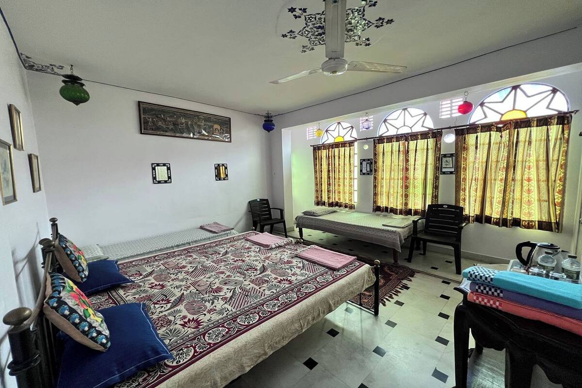 A room with a bed, a desk, a chair, and a window with curtains.